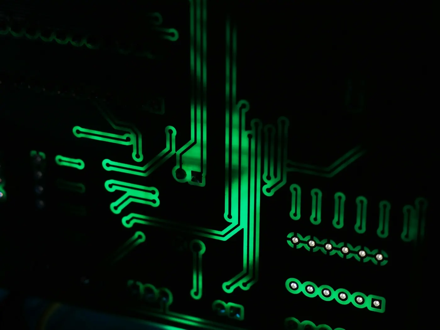 Macro of a motherboard, its circuit traces lit green against black.